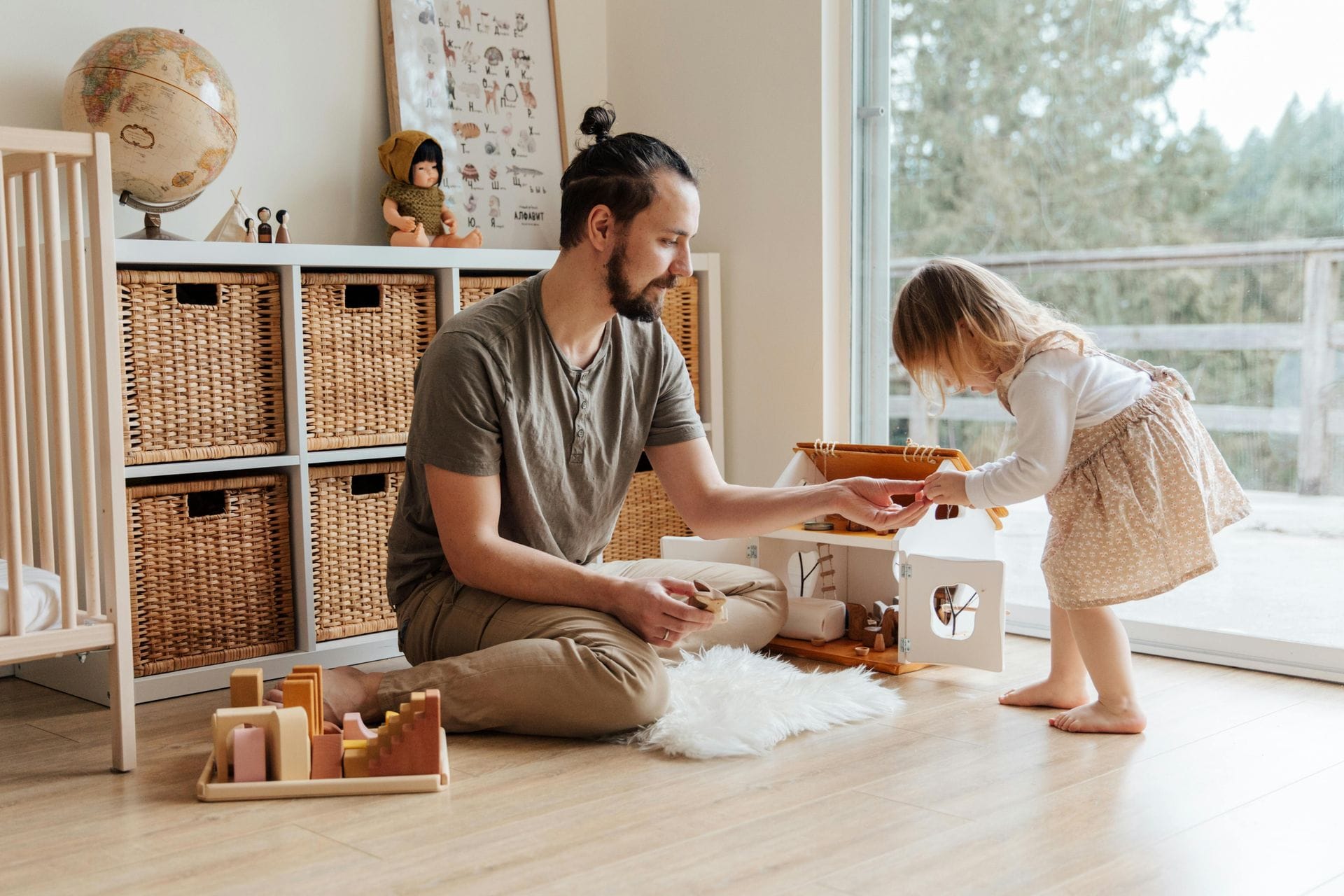 Father ad daughter playing with toys in playroom by a window